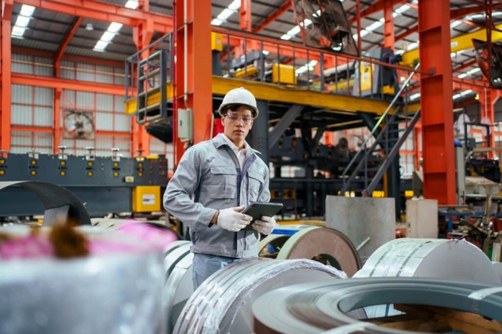 Manufacturing floor operator reviewing a controlled SOP document on a workstation with version history tracked in a document management system