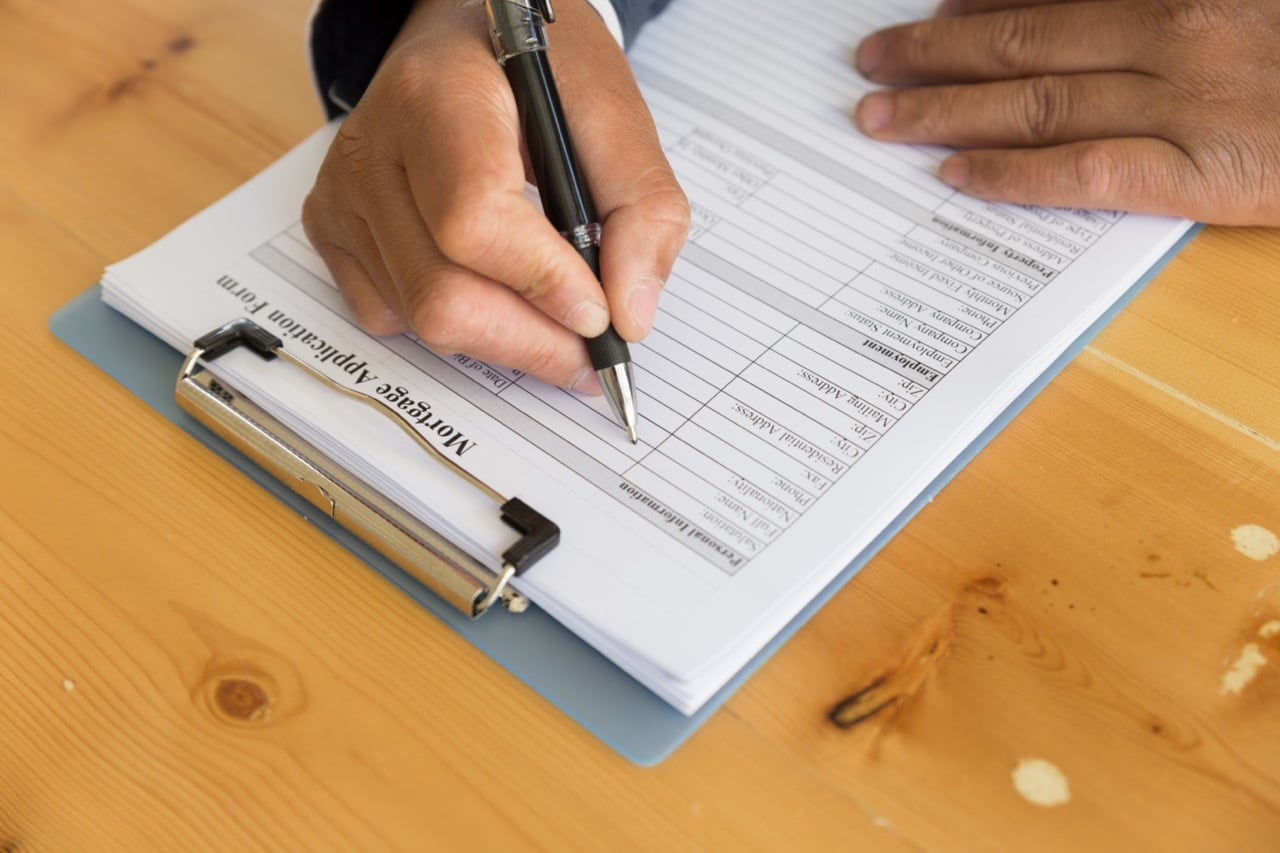 Hand filling out a paper form on a clipboard, the kind of record handled by handwritten document capture